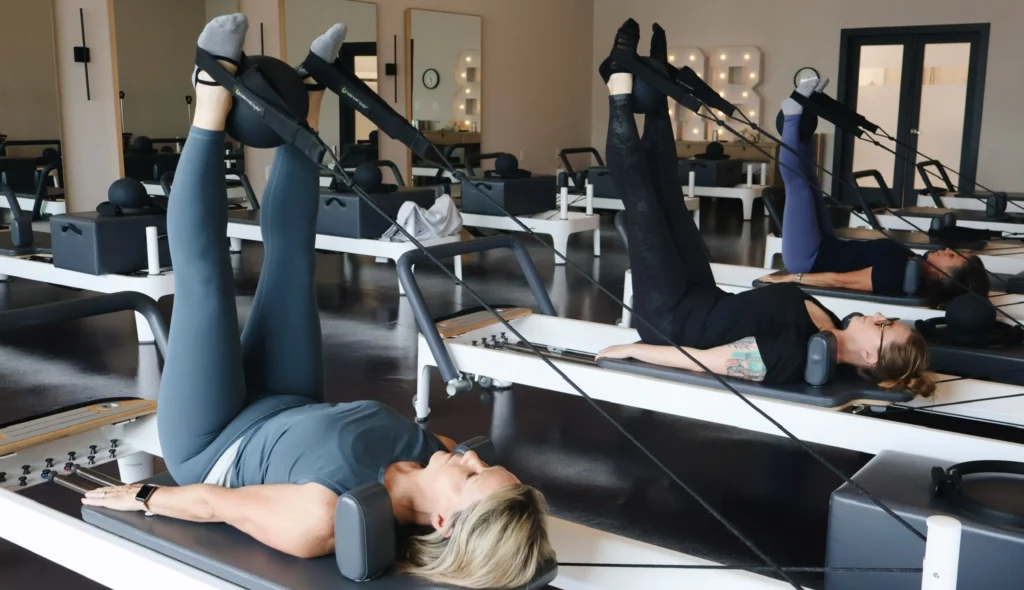 Women doing a leg strap exercise on Balanced Body Reformers during a Pilates class at Right Balance Pilates