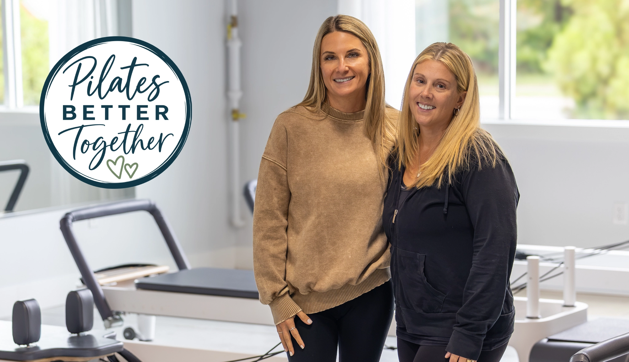 Two friends smiling together beside Reformers at Right Balance Pilates